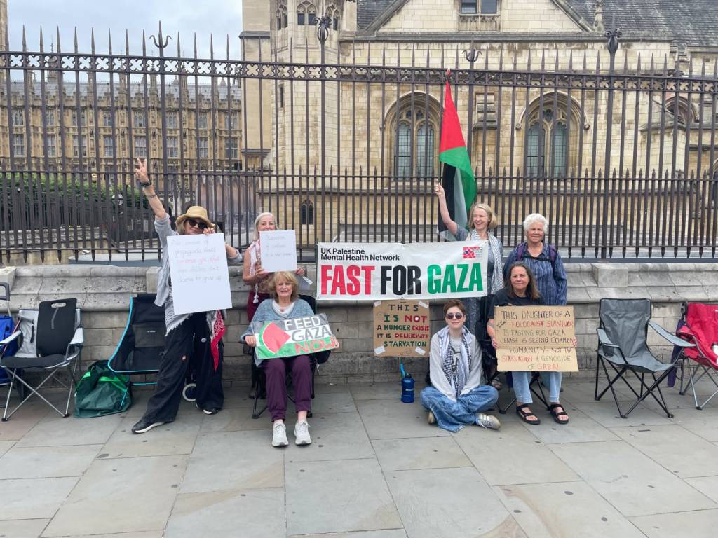 Group of activists gathered outside Parliament for 'Fast for Gaza', holding banners and signs advocating for Gaza and raising awareness about the humanitarian crisis.